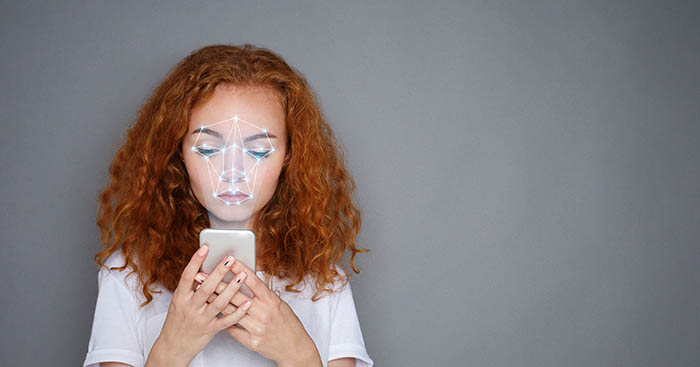 Woman with smartphone using face ID recognition system